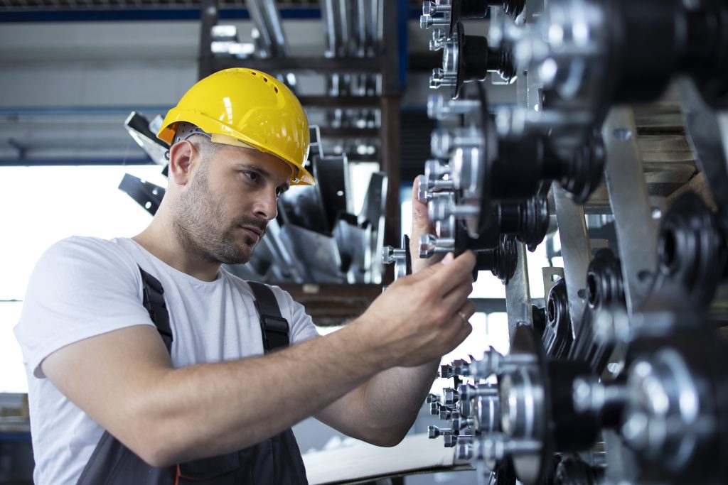 Industrial worker working at production line in factory. Worker inspecting machinery on a production line, highlighting the skilled staffing solutions in manufacturing and maintenance provided by Workvantage.