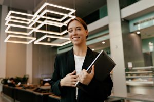 Smiling hospitality manager holding a tablet in the lobby of a modern hotel, highlighting efficient management and customer service at Workvantage.