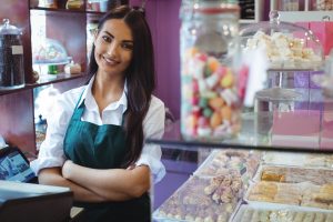 Smiling woman working at a candy store, representing seasonal jobs in the food and hospitality industry.