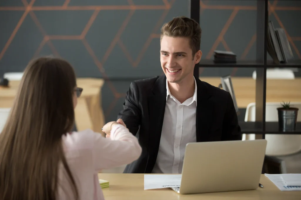 smiling-hr-employer-handshaking-successful-job-applicant-hiring-greeting Employer shaking hands with a candidate during a recruitment meeting for seasonal workers.
