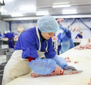 Worker cutting fish in a meat processing facility. Workvantage provides specialized staffing solutions to ensure efficiency and expertise in meat and seafood processing.