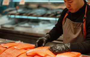 Workvantage worker preparing high-quality salmon fillets in a fish processing facility, ensuring food safety and efficiency.
