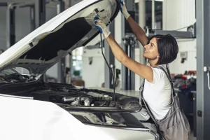 Automotive technician performing specialized skilled trades work under the hood of a car.