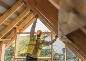 Construction worker measuring a roof structure on a building site, highlighting the specialized construction staffing solutions provided by Workvantage.