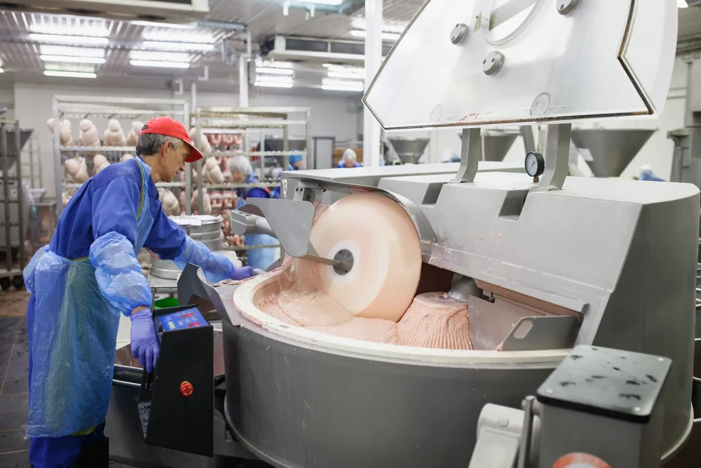 meat-grinder-meat-industry Worker operating industrial equipment in a meat processing plant. Workvantage provides qualified personnel for efficient meat production processes in food industries.