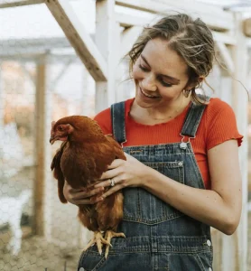 Woman holding a chicken on a farm, representing agricultural work in animal husbandry and Workvantage's recruitment services for the agricultural industry in Canada.