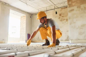 Construction worker installing pipes in the floor during a construction project, highlighting the specialized construction staffing solutions provided by Workvantage.
