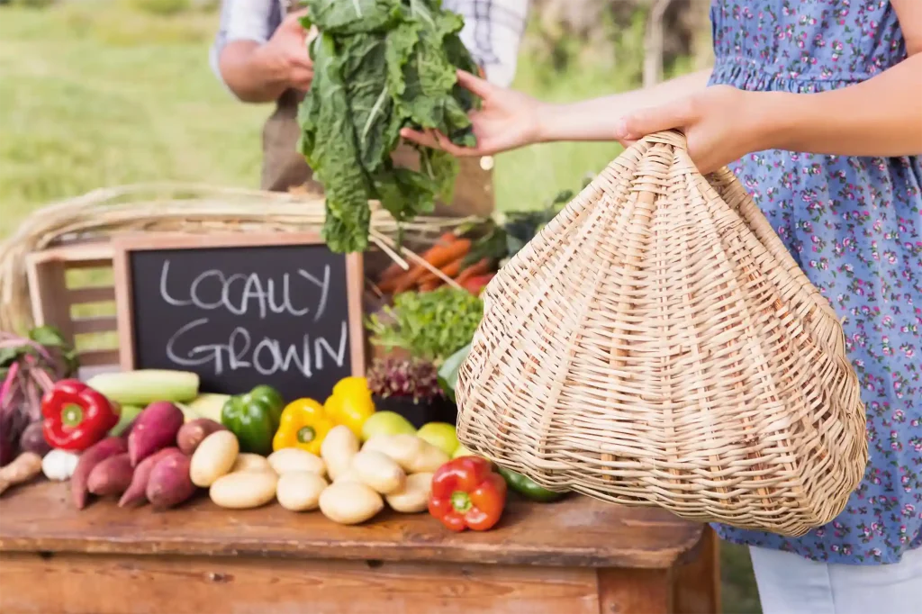 Marché de produits locaux avec légumes frais et pancarte 'locally grown', illustrant le soutien aux fermes locales et à l'agriculture durable.
