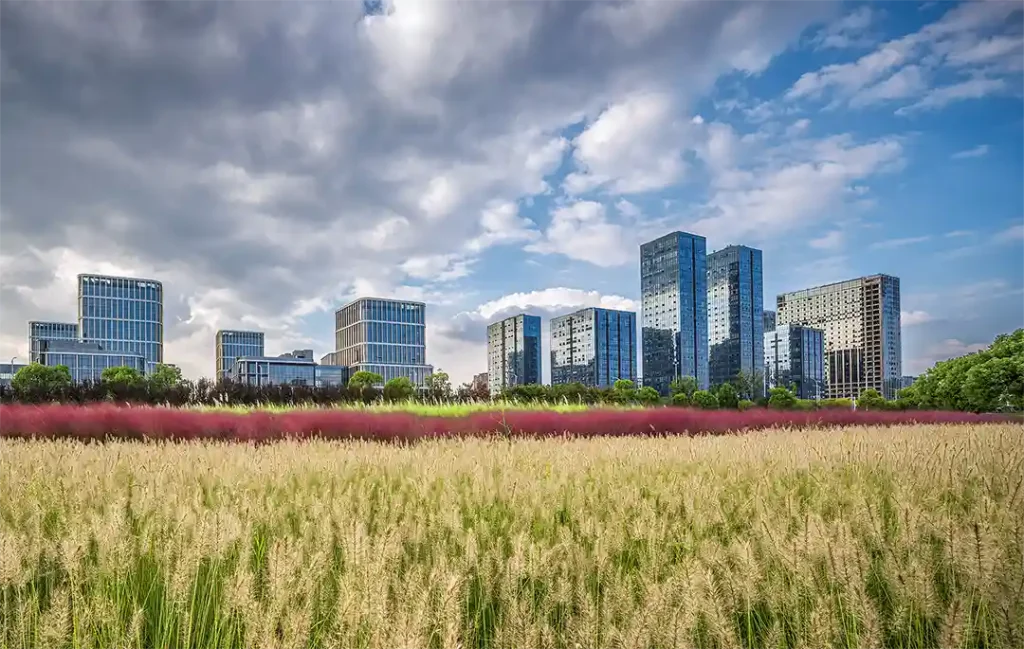 Paysage urbain avec des gratte-ciel entourés de terres agricoles, symbolisant l'impact de l'urbanisation sur les terres arables et l'engagement de Workvantage à fournir des solutions durables.