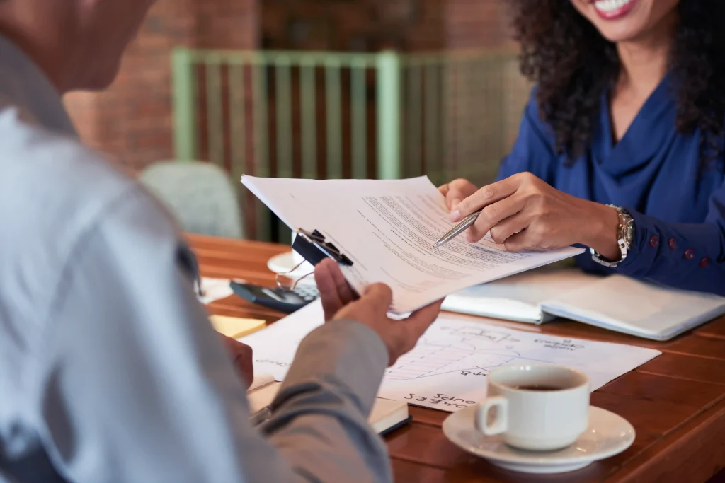 Consultation professionnelle autour de documents administratifs, symbolisant le soutien aux employeurs dans le processus d'EIMT et de recrutement.